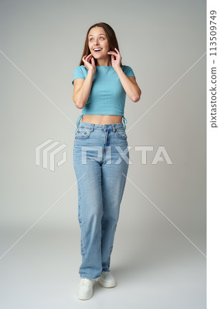 Young woman in blue T-shirt posing to camera on gray background 113509749