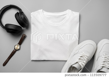 White T-shirt and sneakers, headphones and watch on gray background top view White T-shirt and sneakers, headphones and watch on gray background top view 113509777