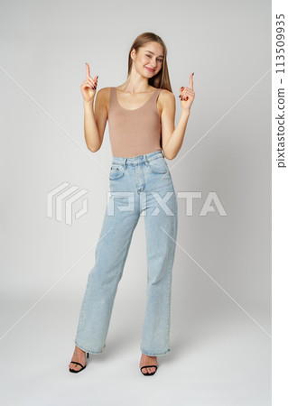 Young Pretty Woman Pointing Finger Up against gray background 113509935