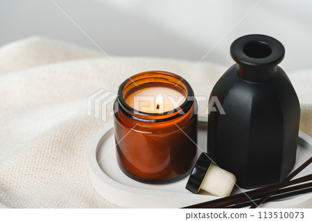 Elegant Aroma Diffuser With Reed Sticks And Scented Candle On White Tablecloth Elegant Aroma Diffuser With Reed Sticks And Scented Candle On White Tablecloth 113510073