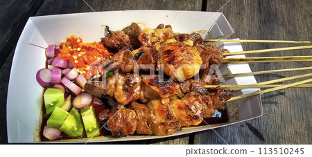 Lamb grilled satay served with barbecue savory sauce and pickled onion, chili and cucumber, selective focus photo 113510245