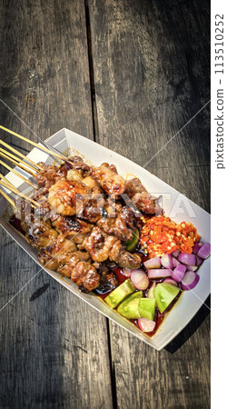 Lamb grilled satay served with barbecue savory sauce and pickled onion, chili and cucumber, selective focus photo 113510252