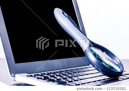 Closeup images of magnifying glass on laptop keyboard 113510382