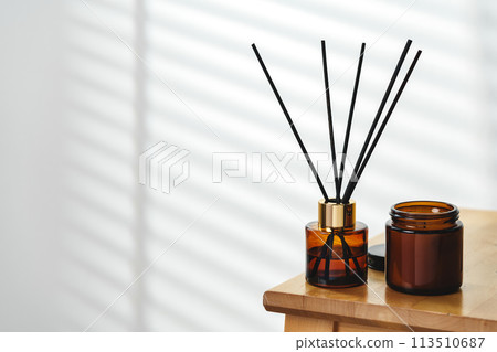 Aromatherapy Reed Diffuser and Scented Candle on a Wooden Table in a Cozy Room 113510687