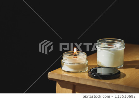 Serene Afternoon Ambiance With a Lit Scented Candle on a Wooden Nightstand 113510692