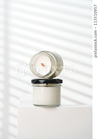 Candle With Extinguished Flame Resting on Glass Jar Near Blinds Candle With Extinguished Flame Resting on Glass Jar Near Blinds 113510957