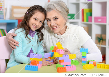 Cute girl and grandmother playing with colorful plastic blocks Cute girl and grandmother playing with colorful plastic blocks 113512062