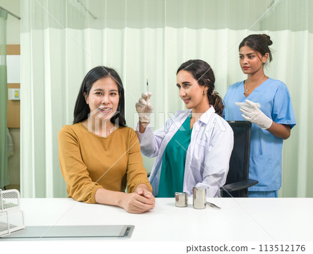 Doctor in white gown and protective glove prepare to give an injection to a female patient. Doctor in white gown and protective glove prepare to give an injection to a female patient. 113512176