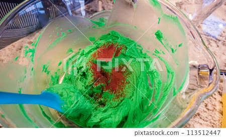 In a well-lit kitchen, an assortment of buttercream frosting in various shades of green and other colors is being meticulously mixed and prepared for the artistic decoration of cupcakes in charming In a well-lit kitchen, an assortment of buttercream frosting in various shades of green and other colors is being meticulously mixed and prepared for the artistic decoration of cupcakes in charming 113512447