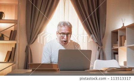 Shocked news. Mature man. Digital communication. Amazed senior male looking laptop with unexpected information in light home interior. 113513317