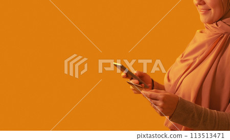 Online shopping. Mobile banking. Unrecognizable happy woman buying purchase with credit card on phone app internet payment on orange empty space background. Online shopping. Mobile banking. Unrecognizable happy woman buying purchase with credit card on phone app internet payment on orange empty space background. 113513471
