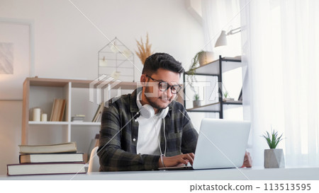 Remote education. Home study. Distance learning. Smiling happy man typing on laptop working on homework college research online at desk workplace. 113513595