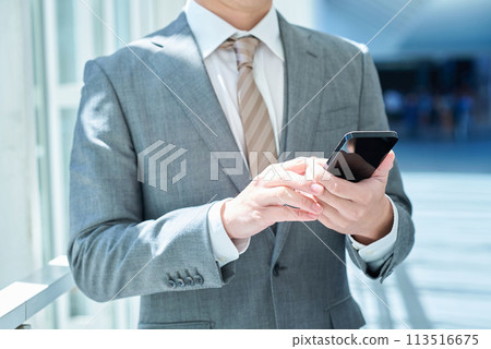 A businessman handling a smartphone A businessman handling a smartphone 113516675