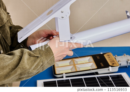 Assembling LED street lighting with solar panel, owner prepares mounting bracket. 113516933