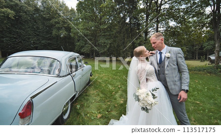 Bride and groom posing in front of white car for wedding picture Bride and groom posing in front of white car for wedding picture 113517175
