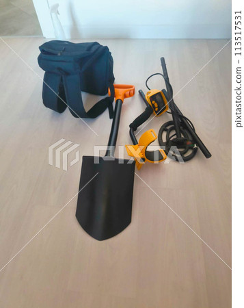 A shovel, a backpack, a coin finder and a metal detector are lying on the floor. A shovel, a backpack, a coin finder and a metal detector are lying on the floor. 113517531