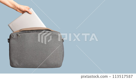 Hand putting laptop notebook into computer bag. Banner background 113517587