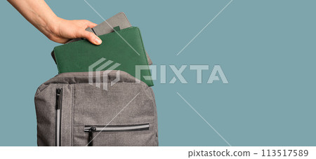Hand putting green planner, business book, textbook, notebook into backpack, school bag. Banner Hand putting green planner, business book, textbook, notebook into backpack, school bag. Banner 113517589