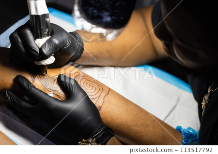 Tattoo artist is concentrated on his work. Closeup. 113517792