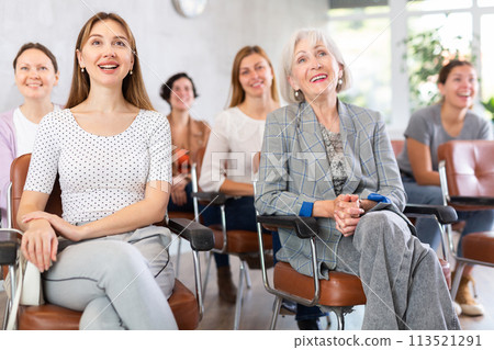 small group of women are sitting in audience, listening to lecture and laugh at amusing case 113521291
