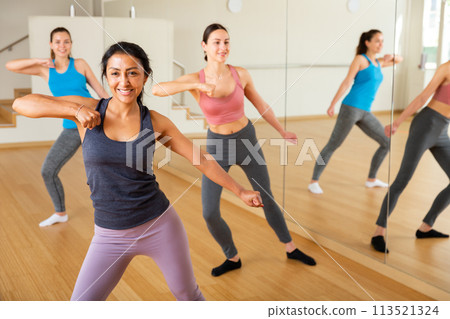Llatin american woman practicing vigorous swing during group training Llatin american woman practicing vigorous swing during group training 113521324