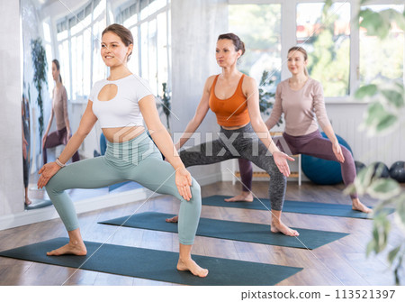 Girl teacher lead lesson, run training in female yoga studio and perform pose of goddess Girl teacher lead lesson, run training in female yoga studio and perform pose of goddess 113521397