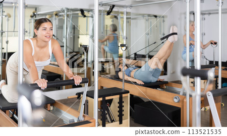 Concentrated young girl practicing exercises on Pilates reformer 113521535