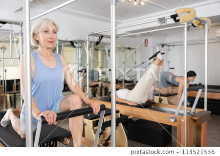 Sporty aged woman doing exercises on Pilates reformer 113521536