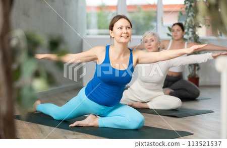 Woman in sportswear using mat spend free time doing sports and yoga for health and wellness together with group people Woman in sportswear using mat spend free time doing sports and yoga for health and wellness together with group people 113521537