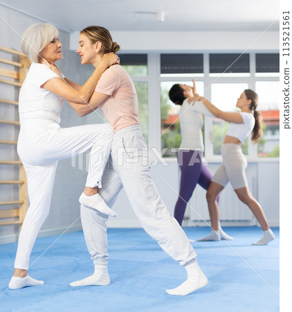 Senior woman performing head hold with knee strike to midsection in training sparring 113521561