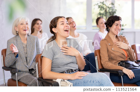 small group of women are sitting in audience, listening to lecture and laugh at amusing case small group of women are sitting in audience, listening to lecture and laugh at amusing case 113521564