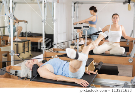 Sporty aged woman doing exercises on Pilates reformer 113521653