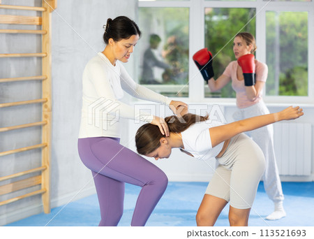 Asian woman performing knee strike to sparring partner face during self-defense training Asian woman performing knee strike to sparring partner face during self-defense training 113521693