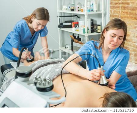 Women doctors performing hardware body procedure to female patient 113521730