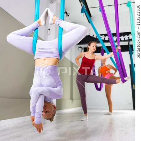 Woman doing inverted butterfly pose in hammock with arms twisted Woman doing inverted butterfly pose in hammock with arms twisted 113521830