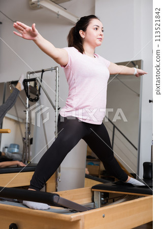Pilates woman in reformer teaser exercise at sport gym Pilates woman in reformer teaser exercise at sport gym 113521842