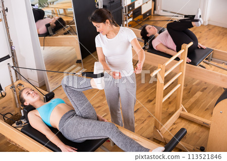 Pilates instructor training women at gym 113521846