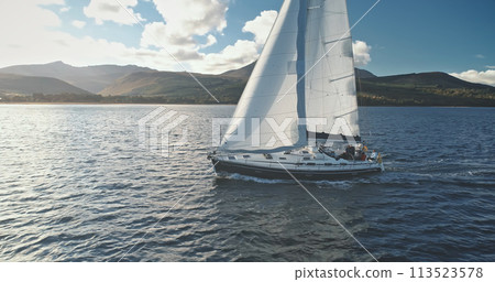 Closeup yacht race at ocean shore with green mountains. Seascape with luxury ship under white sails Closeup yacht race at ocean shore with green mountains. Seascape with luxury ship under white sails 113523578