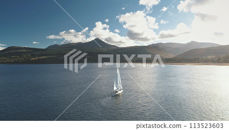 Slow motion of sailing yacht at mountain ocean coast. Sailboat regatta race at sea bay aerial 113523603