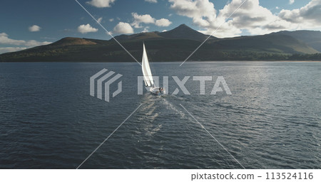 Slow motion of yacht, wind blows to sail at ocean aerial. Mountain island of Arran, Scotland, Europe Slow motion of yacht, wind blows to sail at ocean aerial. Mountain island of Arran, Scotland, Europe 113524116