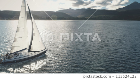 Sun shine over yacht at mountain island coast aerial. Luxury sailboat regatta race at sea. Sunlight Sun shine over yacht at mountain island coast aerial. Luxury sailboat regatta race at sea. Sunlight 113524122