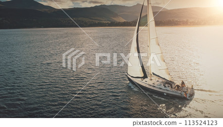 Sun shine over yacht at mountain island coast aerial. Luxury sailboat regatta race at sea. Sunlight 113524123