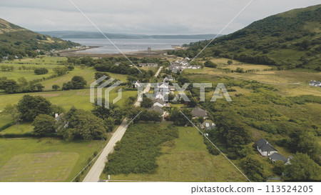 Slow motion of Scottish whisky distillery at village aerial. Road, cottages, houses at green valley 113524205
