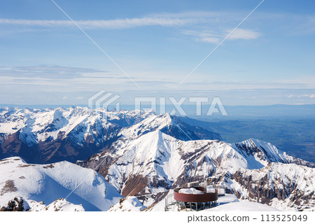 Breathtaking panoramic view of Murren ski resort, Switzerland. Circular building on snowy peak overlooking Swiss Alps under clear blue sky. Ideal for skiing and snowboarding. 113525049