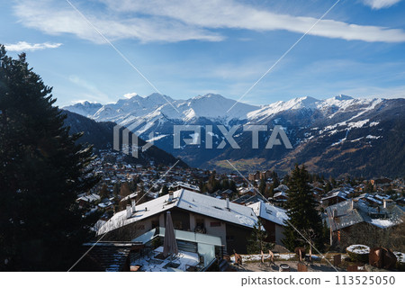 Scenic winter mountain village with snow covered rooftops, chalets, and majestic peaks in the European Alps, possibly in Switzerland, Austria, or France. Scenic winter mountain village with snow covered rooftops, chalets, and majestic peaks in the European Alps, possibly in Switzerland, Austria, or France. 113525050