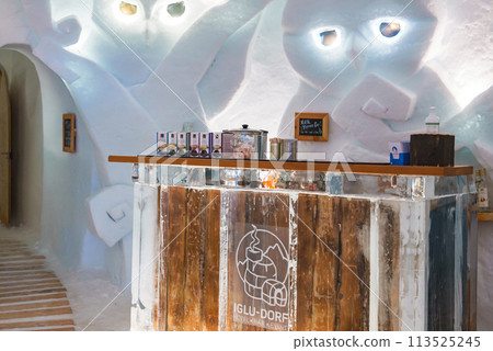 Interior space in ice structure at Zermatt ski resort. IGLU DORF bar with tea dispensers and cups. Serene lighting and cozy atmosphere for warm drinks. 113525245