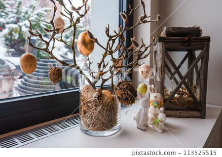 Charming Easter themed luxury hotel display in Zermatt, Swiss ski resort. Glass vase with branches, pastel eggs, rustic lantern, bunny figurines, snowy backdrop. Charming Easter themed luxury hotel display in Zermatt, Swiss ski resort. Glass vase with branches, pastel eggs, rustic lantern, bunny figurines, snowy backdrop. 113525515