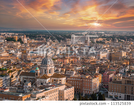 An aerial view of Rome at dusk reveals a sky changing from pink to blue, with the city in golden light. Key buildings and streets showcase its rich history and architectural variety. An aerial view of Rome at dusk reveals a sky changing from pink to blue, with the city in golden light. Key buildings and streets showcase its rich history and architectural variety. 113525839