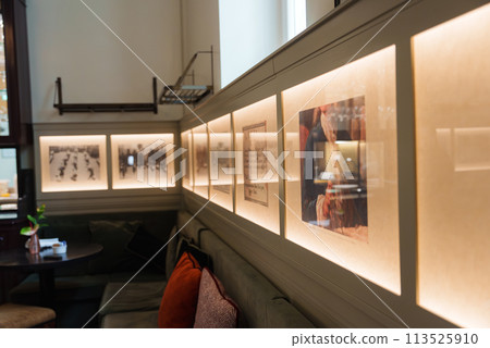 Luxury hotel interior in Rome featuring well lit wall with framed artworks, plush green sofa with red cushions, creating a sophisticated and inviting ambiance. Luxury hotel interior in Rome featuring well lit wall with framed artworks, plush green sofa with red cushions, creating a sophisticated and inviting ambiance. 113525910
