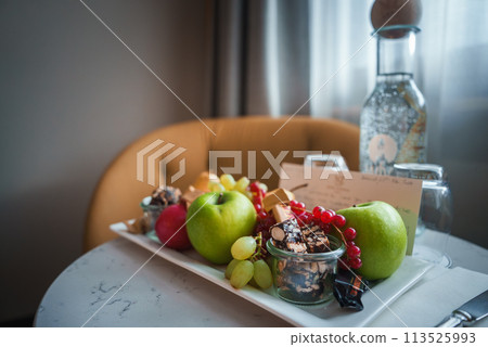 Luxurious hotel guest room in Zermatt, Switzerland, with fresh fruits, gourmet treats, premium water, and welcome note. Cozy, stylish interior ambiance. 113525993